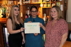 Priti Patel MP presents Dee Hayes, Landlady at the Red Lion public house, with her local hero thank you certificate, alongside Dee’s daughter, Charlie.